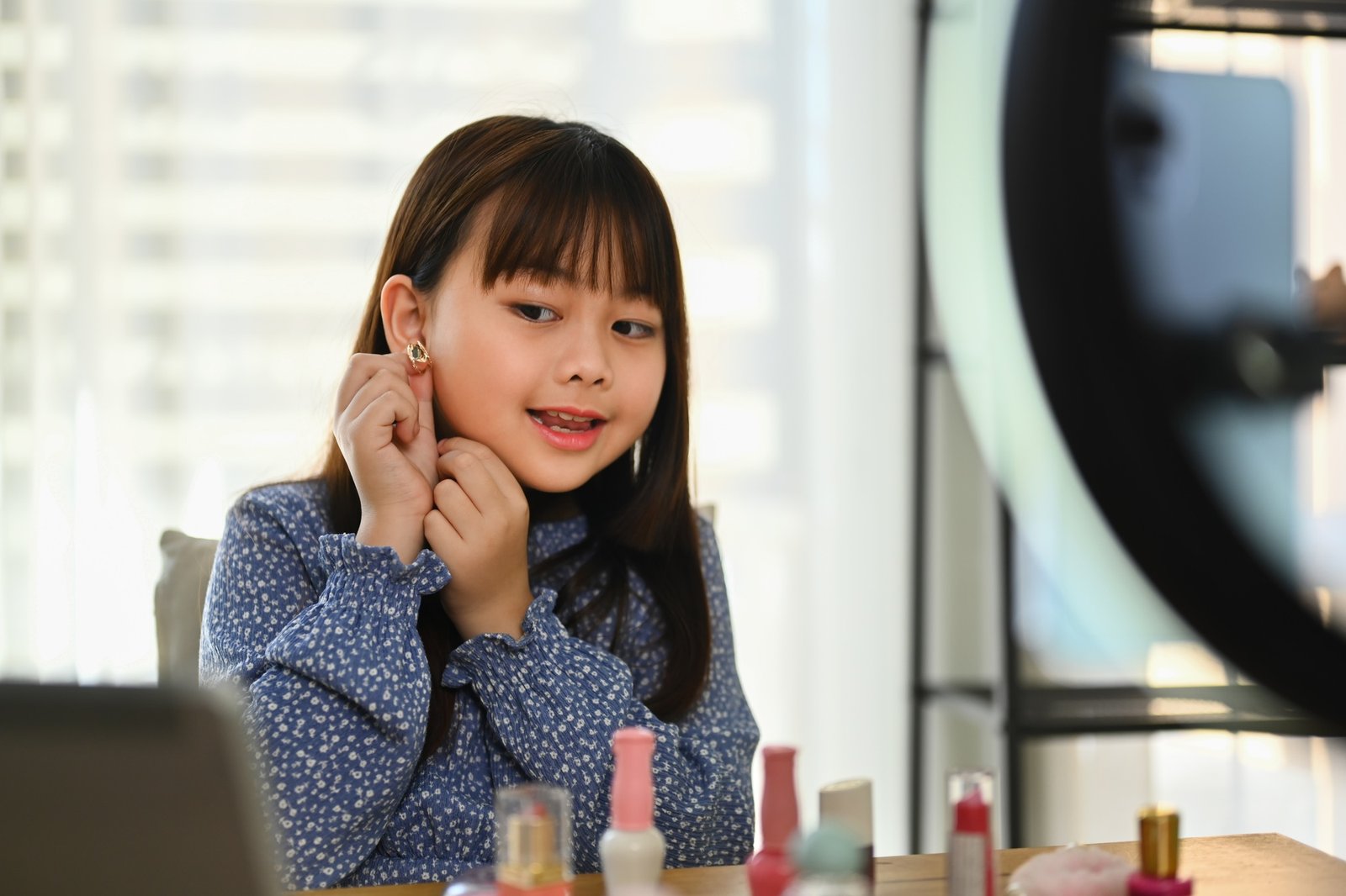 Little Asian girl showing new earrings on ear front of mobile phone camera.